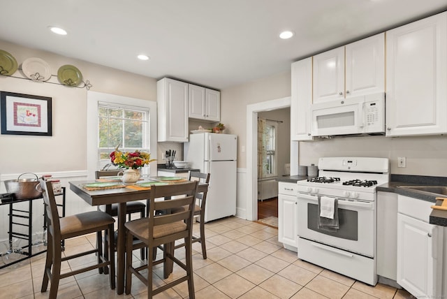 kitchen with white cabinets, white appliances, and light tile patterned flooring