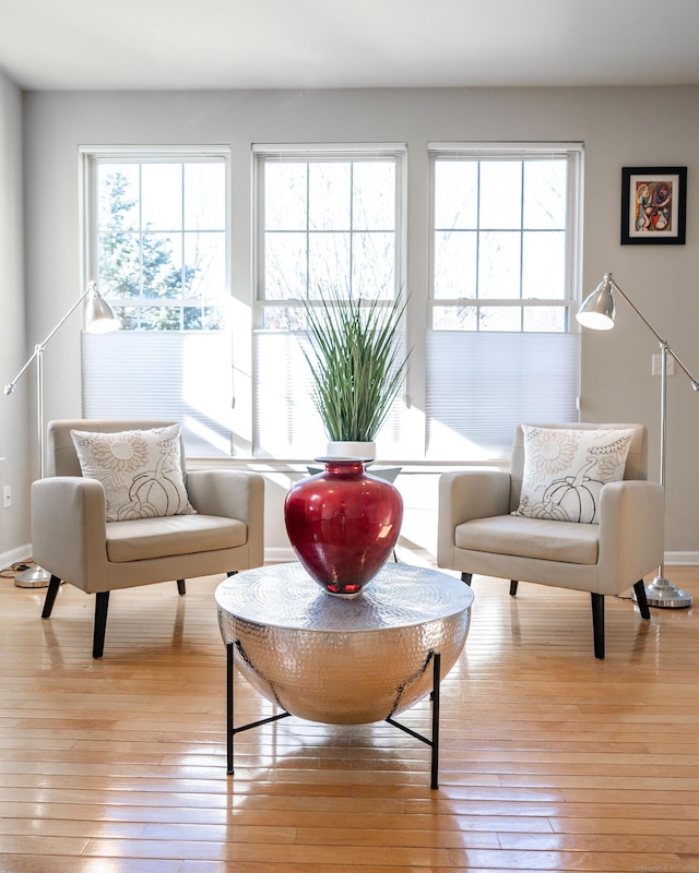 sitting room with plenty of natural light, baseboards, and light wood-style floors