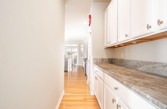 corridor featuring baseboards and light wood finished floors