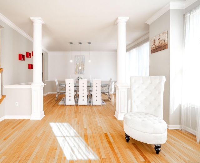 dining space featuring decorative columns, baseboards, crown molding, and light wood finished floors