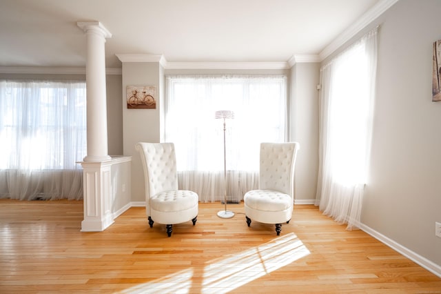 sitting room with light wood finished floors, plenty of natural light, and ornate columns