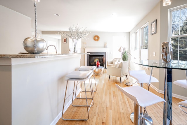 kitchen with baseboards, a glass covered fireplace, and light wood finished floors