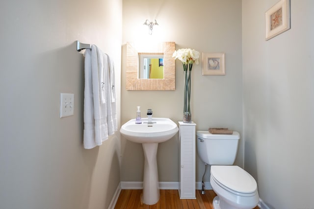 bathroom featuring toilet, wood finished floors, and baseboards