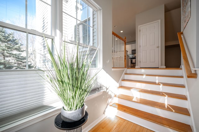 stairway featuring a healthy amount of sunlight and hardwood / wood-style floors