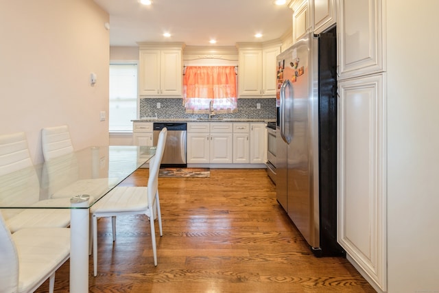 kitchen with stainless steel appliances, white cabinets, sink, backsplash, and light hardwood / wood-style flooring