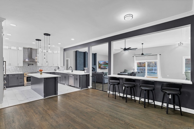 kitchen with wood-type flooring, gray cabinets, sink, white cabinets, and wall chimney exhaust hood