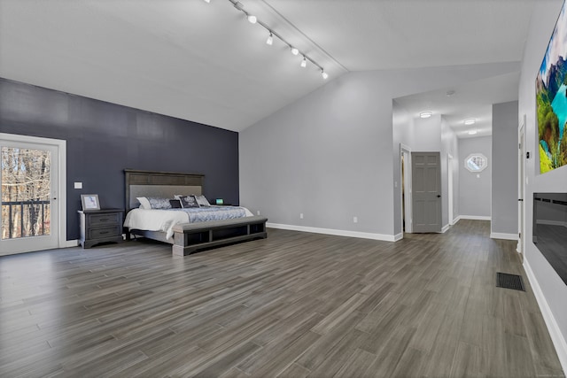 bedroom featuring vaulted ceiling, hardwood / wood-style flooring, track lighting, and access to exterior