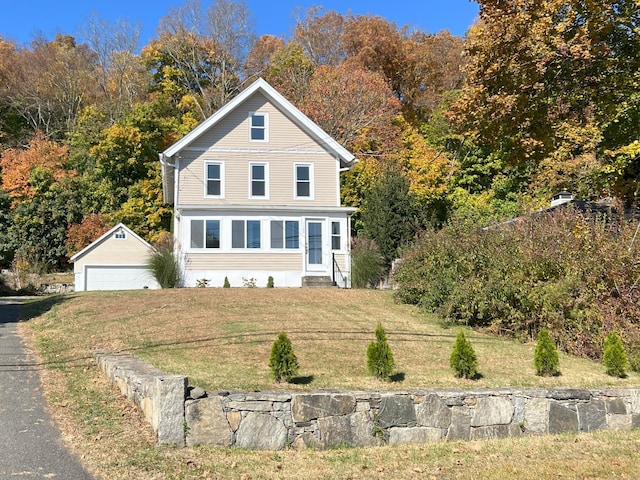 view of front of house with a garage, an outbuilding, and a front lawn