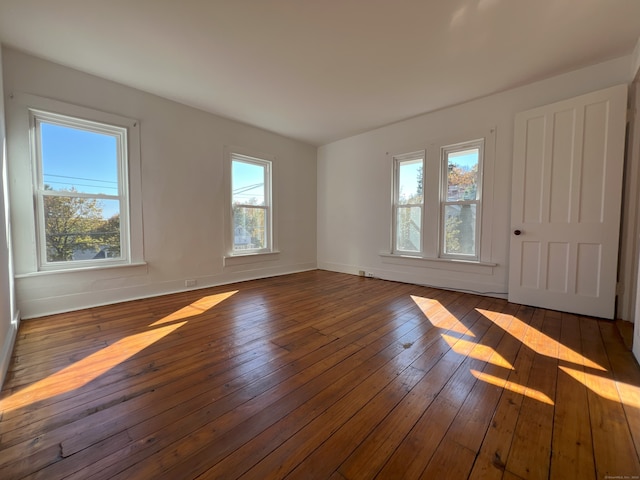 unfurnished room with dark hardwood / wood-style flooring and plenty of natural light