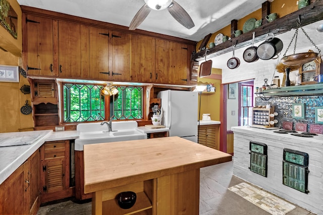 kitchen featuring ceiling fan, sink, a center island, and white refrigerator