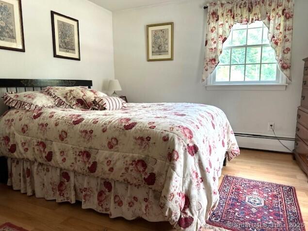 bedroom featuring baseboard heating and wood finished floors