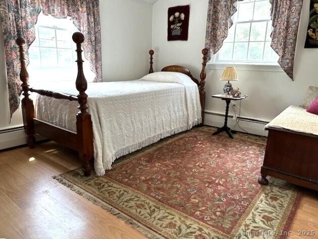 bedroom featuring a baseboard heating unit and wood finished floors