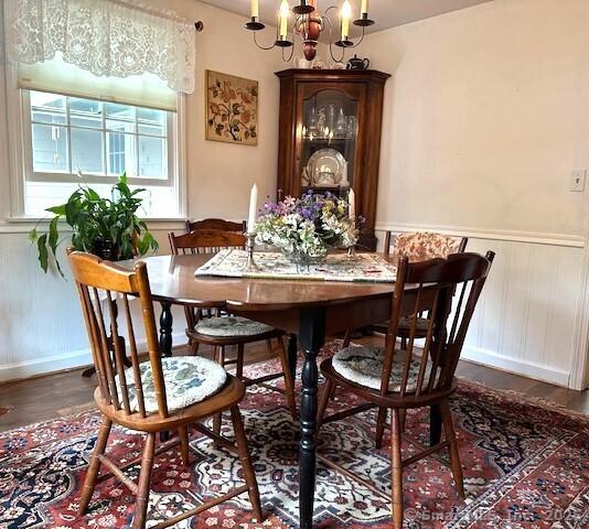 dining space with wainscoting, an inviting chandelier, and wood finished floors