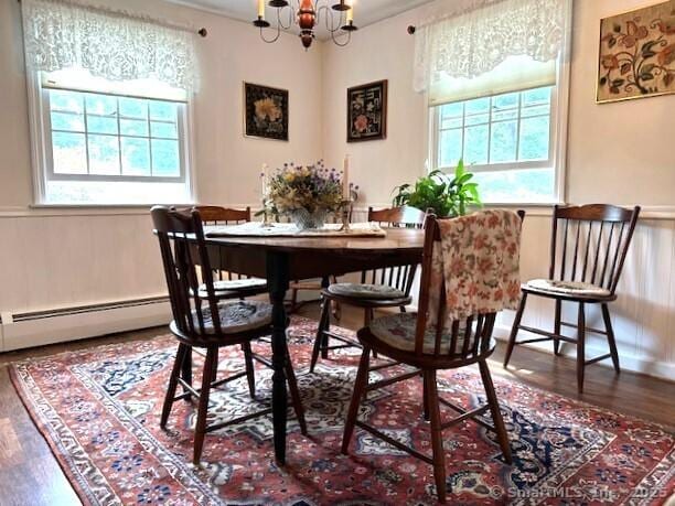 dining room with an inviting chandelier, wood finished floors, and a baseboard radiator