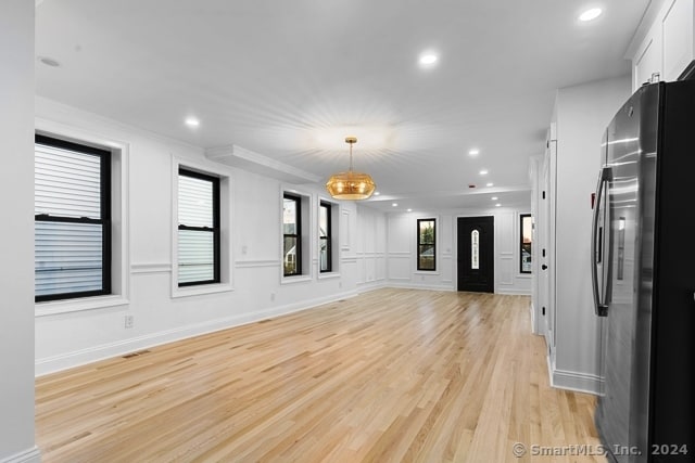 spare room with a chandelier, light wood-type flooring, and crown molding