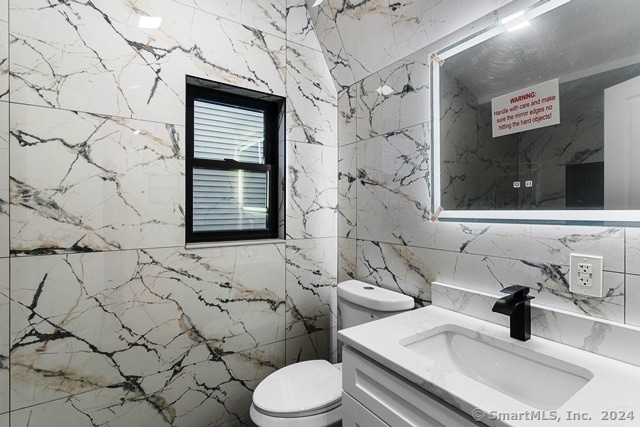 bathroom featuring tile walls, vanity, and toilet