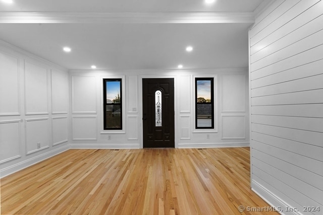 foyer entrance with light wood-type flooring and ornamental molding