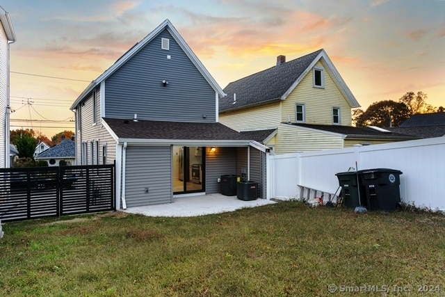 back house at dusk with a yard and a patio area