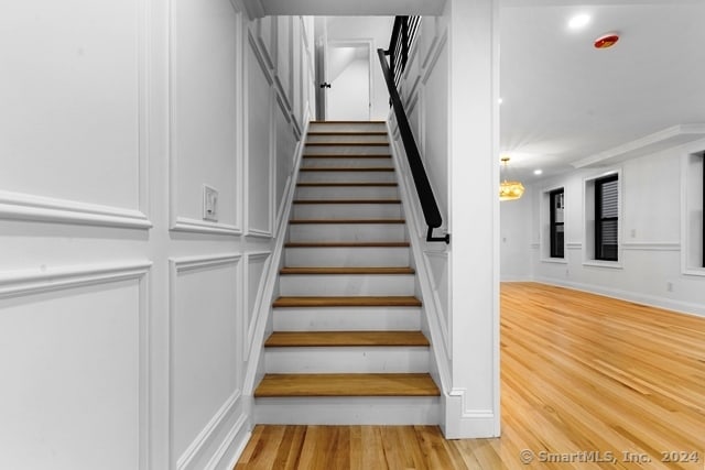 stairs featuring hardwood / wood-style floors and a chandelier