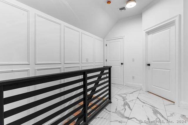 45 Stevens St, Milford, CT 06460 - hall with light marble finish flooring, vaulted ceiling, and a decorative wall