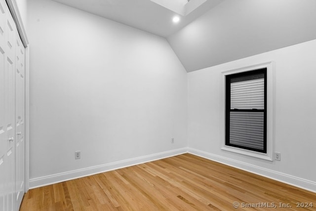 spare room featuring hardwood / wood-style flooring and lofted ceiling with skylight