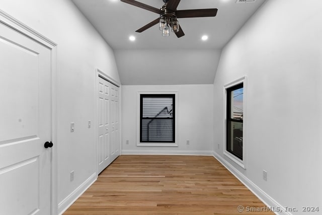 empty room with vaulted ceiling, ceiling fan, and light hardwood / wood-style flooring