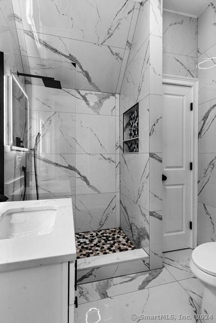 bathroom with toilet, vanity, and a tile shower