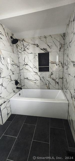 bathroom with tub / shower combination, tile walls, and tile patterned flooring