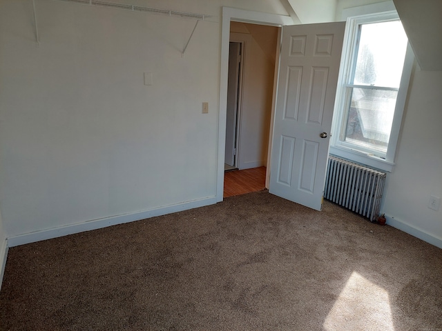 empty room with radiator and dark colored carpet