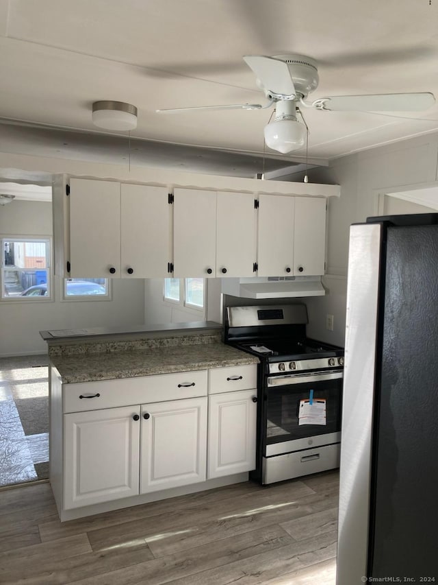 kitchen featuring stainless steel range with gas cooktop, refrigerator, and white cabinetry