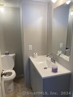 bathroom with toilet, vanity, and tile patterned floors