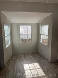 empty room with hardwood / wood-style floors and vaulted ceiling