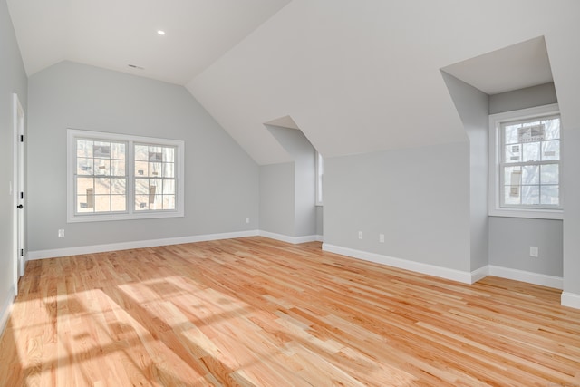 additional living space with light hardwood / wood-style flooring, a wealth of natural light, and lofted ceiling