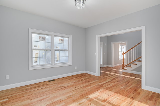 spare room featuring light wood-type flooring and a healthy amount of sunlight