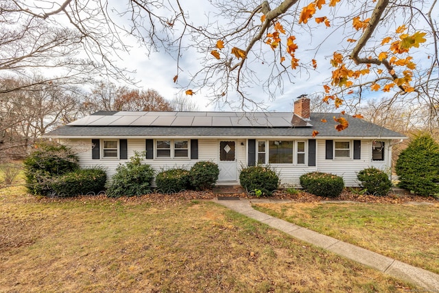 ranch-style home featuring solar panels and a front lawn