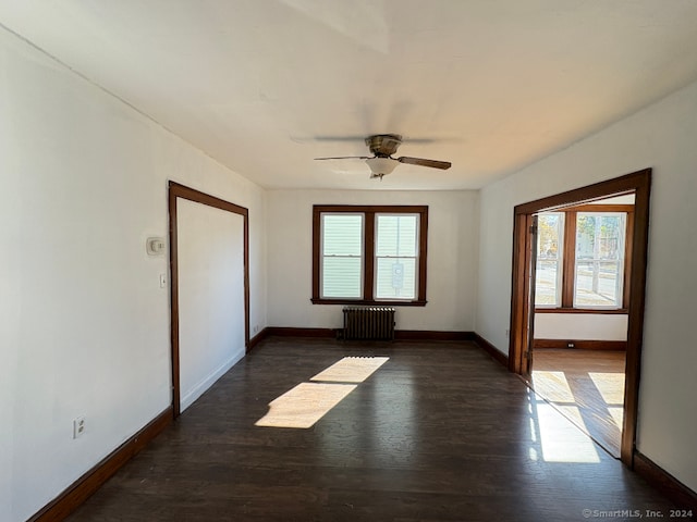 unfurnished room with dark wood-type flooring, radiator heating unit, and ceiling fan