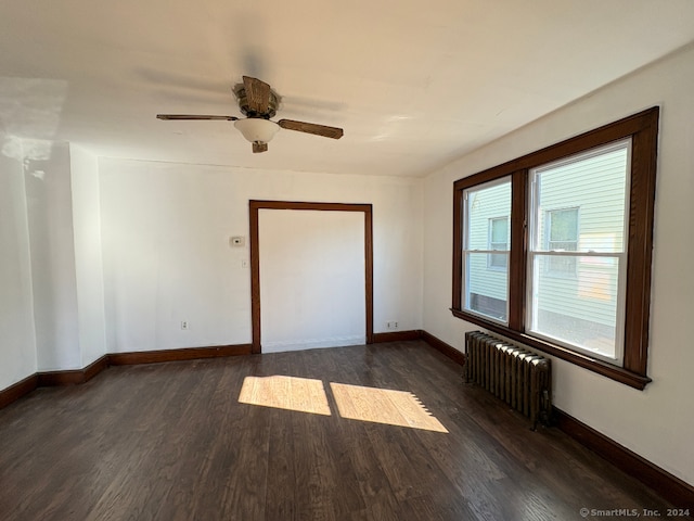 spare room with radiator heating unit, dark wood-type flooring, and ceiling fan