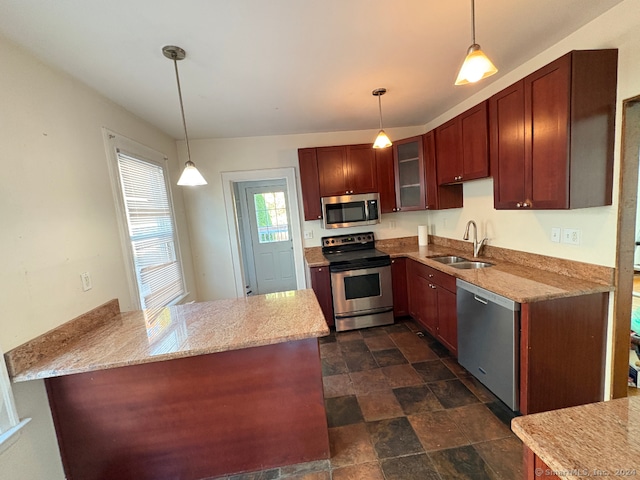 kitchen featuring kitchen peninsula, appliances with stainless steel finishes, sink, and hanging light fixtures