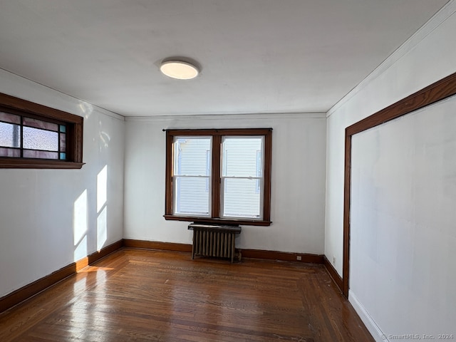 empty room with radiator, dark hardwood / wood-style floors, and crown molding