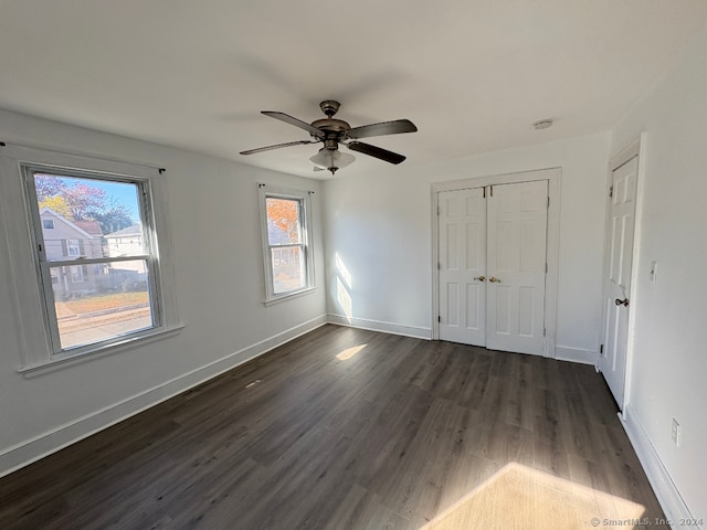 unfurnished bedroom with ceiling fan, dark hardwood / wood-style floors, and a closet