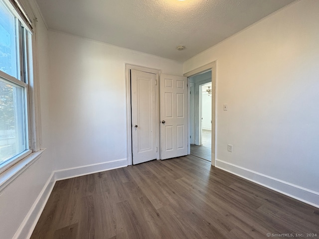 unfurnished bedroom featuring dark wood-type flooring, a textured ceiling, and a closet