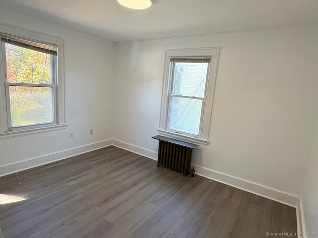 spare room featuring radiator and dark hardwood / wood-style floors