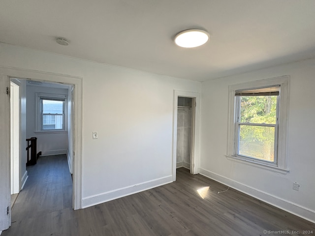 unfurnished bedroom with dark hardwood / wood-style flooring and a closet