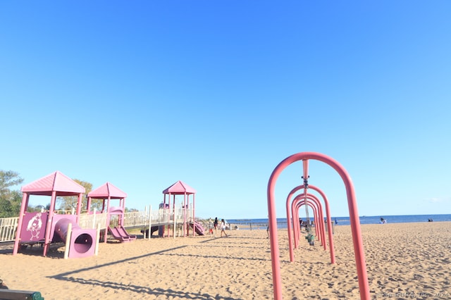 view of jungle gym with a beach view and a water view