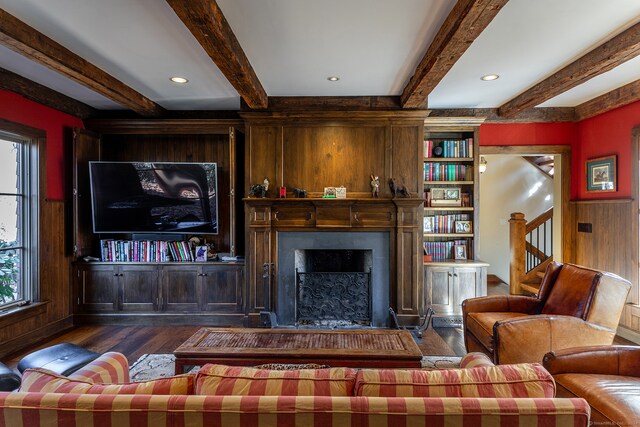 living room featuring beamed ceiling, dark hardwood / wood-style flooring, and wooden walls