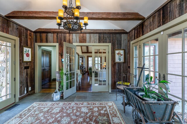 foyer entrance featuring french doors, lofted ceiling with beams, a notable chandelier, and wood walls