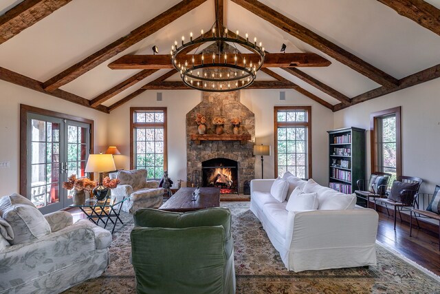 living room featuring high vaulted ceiling, french doors, a stone fireplace, a notable chandelier, and wood-type flooring