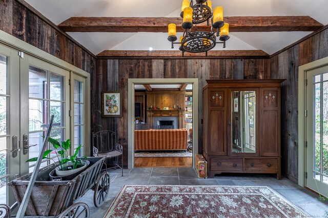 foyer entrance with vaulted ceiling with beams, french doors, wooden walls, and a chandelier