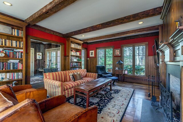 living room with wood walls, dark hardwood / wood-style flooring, beamed ceiling, and french doors