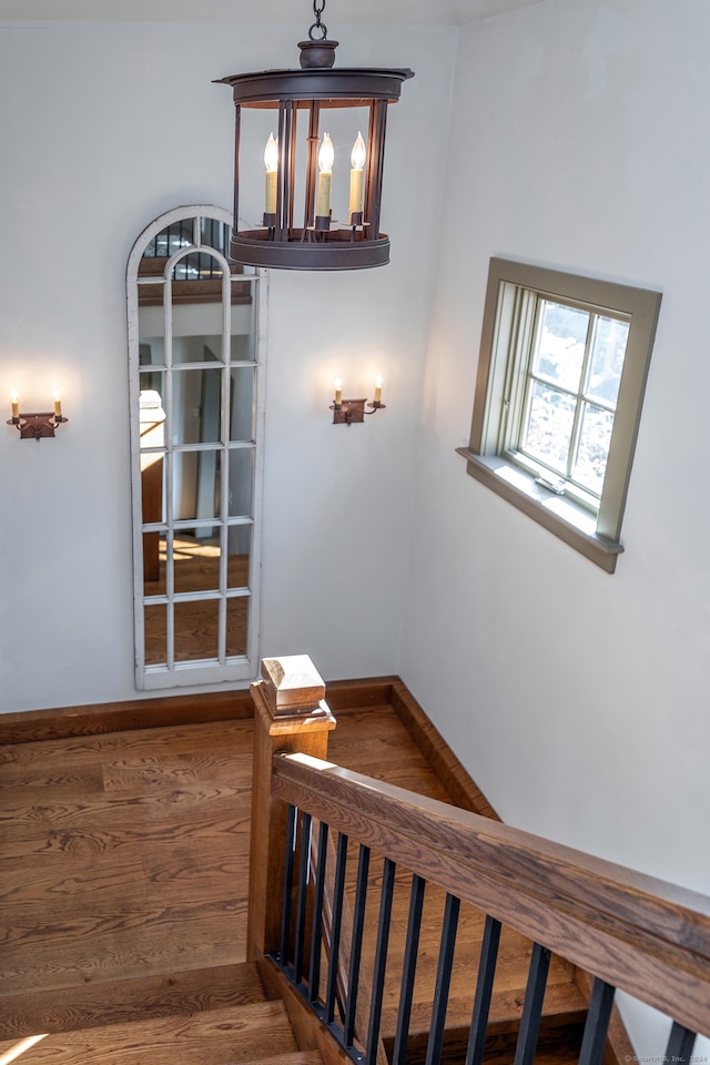 stairs with hardwood / wood-style floors and an inviting chandelier